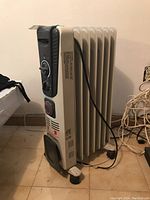 Side view of the Intertek oil filled radiator heater showing the fins, control dials, wheels and power cord.