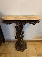 Front and side view of console table showing marble top and detailed ornate base with figures.