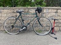 Full side view of bicycle with bag and pump leaning against stone wall
