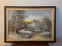 Full view of the framed landscape painting showing the snowy mountain cabin scene.