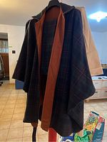 Plaid wool duster coat with brown inner lining hanging on a hanger, shown from the front side