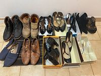 Top down photo of the lot showing 11 pairs of men's and women's shoes in various styles and colors, arranged in front of a beige wall.