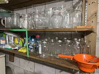 Top shelf showing multiple clear glass vases and pitchers of various shapes and sizes, arranged in a row.