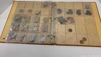 Binder open showing two pages filled with Canadian coins in clear plastic pockets, coins varying in size and condition.