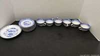 Full view of 6 cups and 6 saucers laid out on a black surface