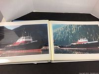 Photo album open showing two large photos of Seaspan tugboats with visible markings and scenic waterfront background