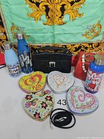 Full lot photograph showing all items on display including water bottles, purse, tins, jewelry, and strap