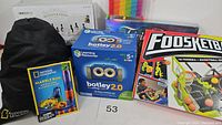 Lot of children's activity and games including Botley 2.0 coding robot box, National Geographic Marble Run with black bag, Foosketball game box, and parts of other games.