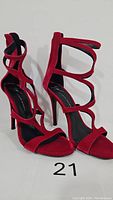 Front view of red velvet high heel sandals with multiple straps and open toe.