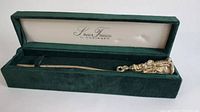 Full view of silver Santa Claus candle snuffer laid inside green velvet box with lid open, showing interior lining and branding
