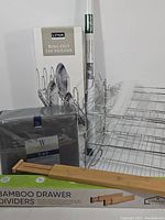 Photo showing all included items: Wamsutta sheet set in packaging, bamboo drawer dividers, metal can roller rack, roll of white window film, and Lynk roll out lid holder boxed.