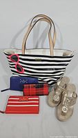 Full lot display showing black and white striped Kate Spade tote bag, three wallets, and gold Jack Rogers sandals