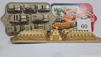 Photo showing the Winter Wonderland Car Cake Pan with 5 car/truck shaped molds and the gold-tone Train Cake Pan in front.