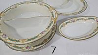 Five pieces of Noritake Althea dishware including large oval platter, dinner plate, large divided bowl, oval serving bowl, and small bowl.