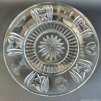 Top view of the clear crystal plate showing the starburst center, ribbed ring, and cut designs around the rim.