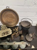Photo showing copper strainer, cast iron bean pot, several sleigh bells including large cast iron bell and smaller bells; cast iron soap dish also visible.