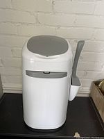 Front view of white Cat Litter Locker with grey lid and side scoop holder, showing overall exterior design and condition.