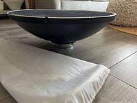 Photo of black 22-inch beauty dish placed on floor showing universal mount and dish curvature.