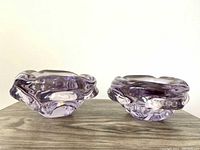 Two translucent lilac purple vintage glass bowls with organic shapes, placed side by side on a wood surface.