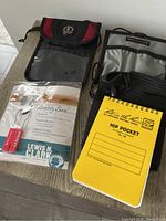 Photo showing passport holder, water bottle holder, safety seal package, and yellow hip pocket notebook.