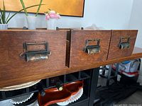 Front view of three vintage wooden filing drawers with metal handles and label holders, showing exterior details and finish.