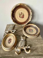 Five-piece set including three framed petit-point artworks with floral and bird designs and two cast iron owl wall hooks, all refinished in metal grey and antique gold.