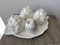Photo of the wood tray holding three white resin artichokes and a ceramic egg on a wood surface