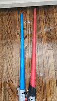 Full length photo of both light sabers showing blue and red blades and handles.