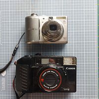 Top front view of Canon compact camera with 4x optical zoom and 12.1MP, and Canon 38mm f/2.8 auto focus film camera.