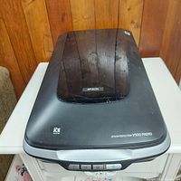 Front view of the Epson Perfection V500 Photo scanner showing the top lid with branding and control buttons on the front.