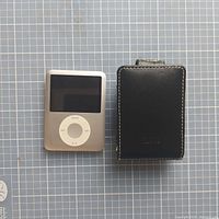 Photo showing front view of silver Apple iPod Classic and accompanying black leather case with stitching detail.