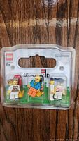 Front view of sealed plastic case containing 3 LEGO LEGOLAND mini figures on wooden surface.