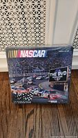 Photo of front of sealed NASCAR DVD board game box showing logo, race cars, and title.