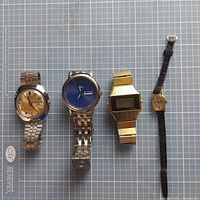 All four watches laid out on a grid background showing front face and bracelet/band details