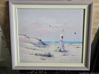 Framed oil painting showing woman and child at seaside with signature visible