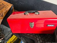Closed view of red Torin metal toolbox with black handle and metal latch.