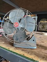 Front angled view of the vintage Torcan electric desktop fan showing the four metal blades and protective wire cage with the central red and white Torcan badge.