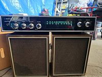 Front view of Sanyo IC Solid State DC vintage radio with FM/AM tuner dial and control knobs, and two brown cloth speakers below