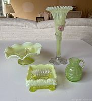 Overview of 4 green glass pieces on table: jug, square dish, ruffled dish, tall vase
