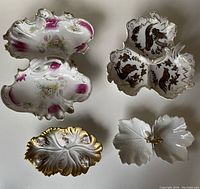 Four assorted antique decorative candy and nut dishes arranged on white surface, showing varying styles and gilded accents.