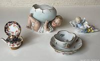 Overview of all items including two bisque figurines, miniature teapot with plate on stand, and miniature cup and saucer