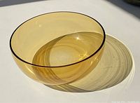 Amber-colored clear fruit bowl, 8.5 inches diameter, shown in daylight casting shadow