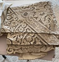 Close-up of folded tablecloths showcasing intricate floral embroidery and cutwork with overlapping layers