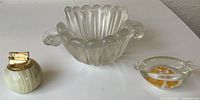 View of the opalescent frosted glass fruit bowl, onyx cigarette lighter, and hand-blown glass ashtray arranged on a white surface.