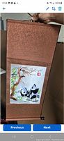 Full view of brown silk scroll with two panda bears artwork in the center, showing hanging rod and textured silken fabric border.