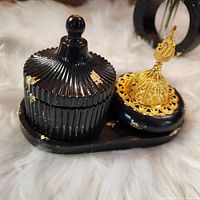Close-up of lidded container and incense burner showing black Jesmonite clay with gold leaf and intricate gold lattice top
