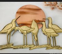 Close-up view of brass seagulls and copper sun wall art depicting bird details and copper patina