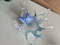 Top angled view of the Murano art glass bowl, showing the clear glass wave-like structure and blue and white coloring in the center.