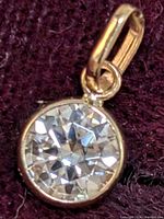 Close-up image showing the front view of the 10K gold pendant with the round moissanite gemstone set in a bezel.