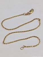 10K gold anklet laid out loosely showing chain detail and clasp